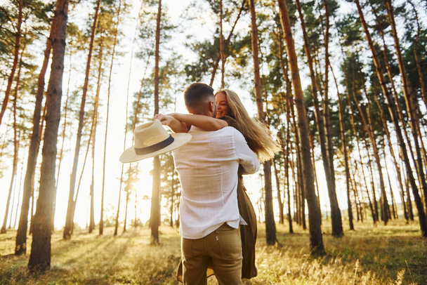 Embracing and kissing. Happy couple is outdoors in the forest at daytime. - Photo, image