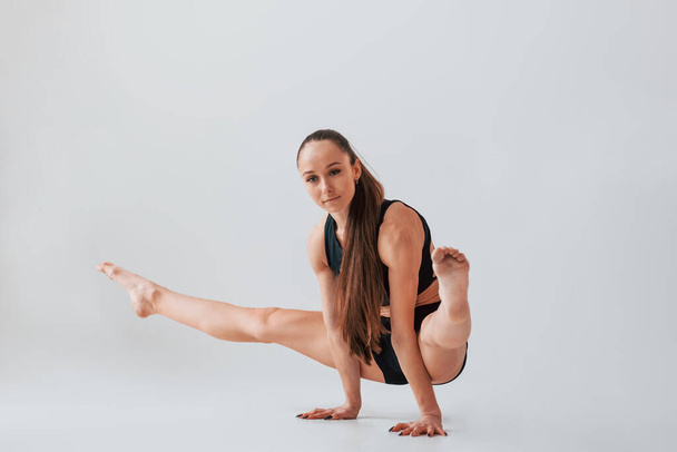 Стоя на руках. Молодая женщина в спортивной одежде занимается гимнастикой в помещении. - Фото, изображение