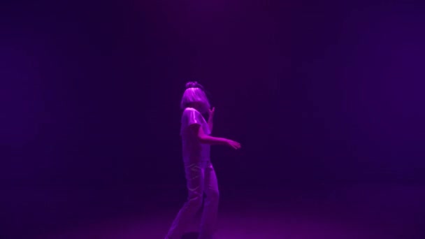 Felice ragazza ballando vr auricolare in luci al neon. Futuristico millenario godendo di simulazione digitale nel ciberspazio buio. Energetico giocatore non riconosciuto in movimento gioco virtuale. Futuro concetto di intrattenimento - Filmati, video