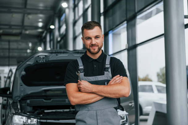 Arms crossed. Man in uniform is working in the autosalon at daytime. - Zdjęcie, obraz