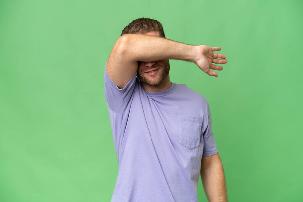 Young handsome caucasian man isolated on green chroma background covering eyes by hands - Φωτογραφία, εικόνα