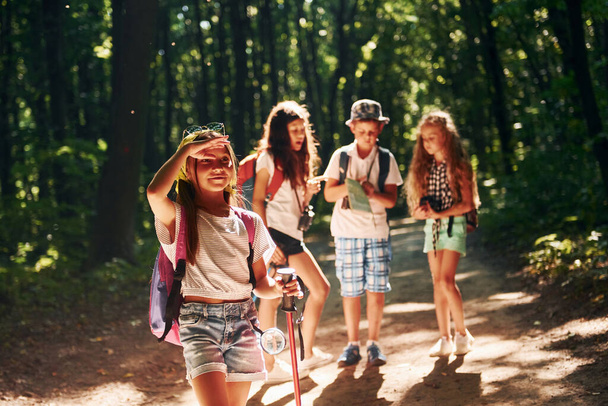 Girl looking far away. Kids strolling in the forest with travel equipment. - Фото, изображение