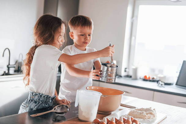 New year anticipation. Little boy and girl preparing Christmas cookies on the kitchen. - Foto, afbeelding