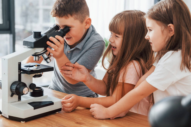 With microscope. Kids having fun in the domestic room at daytime together. - Foto, Bild