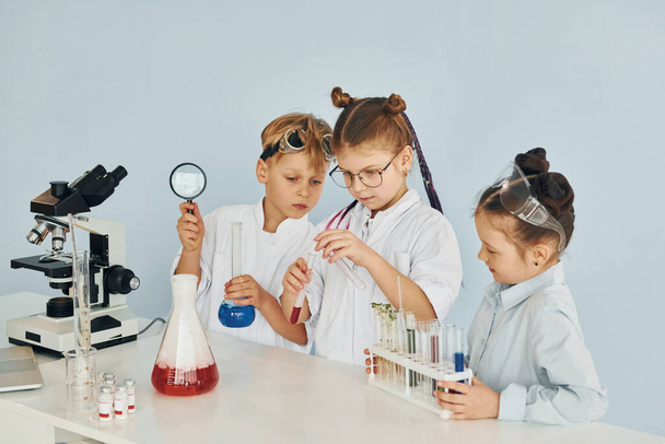 Children in white coats plays a scientists in lab by using equipment. - Foto, Bild
