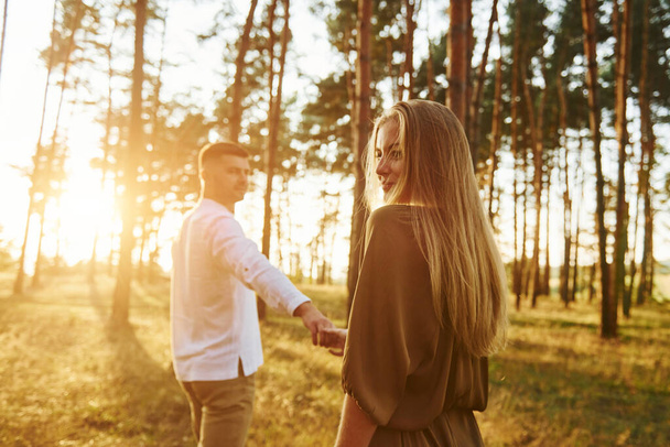 Having a walk. Happy couple is outdoors in the forest at daytime. - Fotoğraf, Görsel