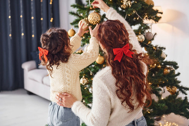 Decorating tree. Mother with her little daughter is at home. - Fotografie, Obrázek