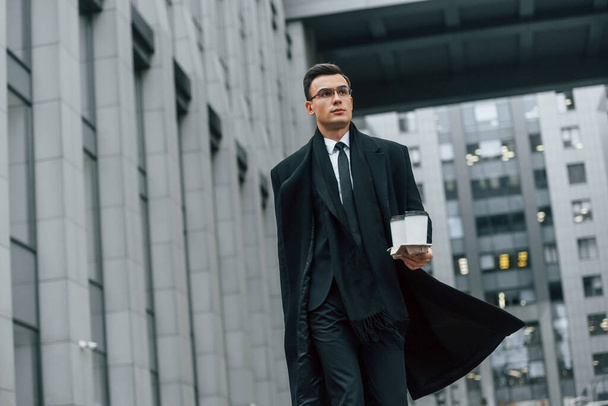 Walking forward. Businessman in black suit and tie is outdoors in the city. - Fotó, kép