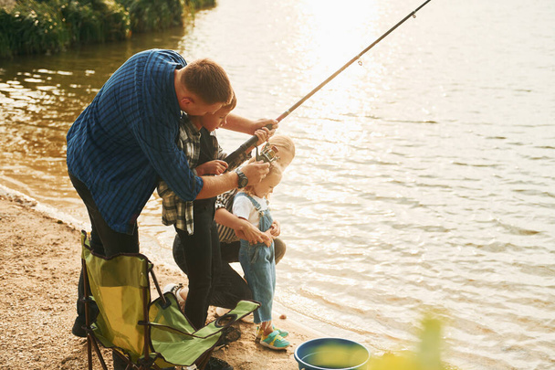 Learning to fishing. Father and mother with son and daughter together outdoors at summertime. - Foto, immagini