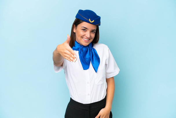stewardessa samolot kaukaska kobieta odizolowany na niebieskim tle ściskając dłonie za zamknięcie dobry interes - Zdjęcie, obraz