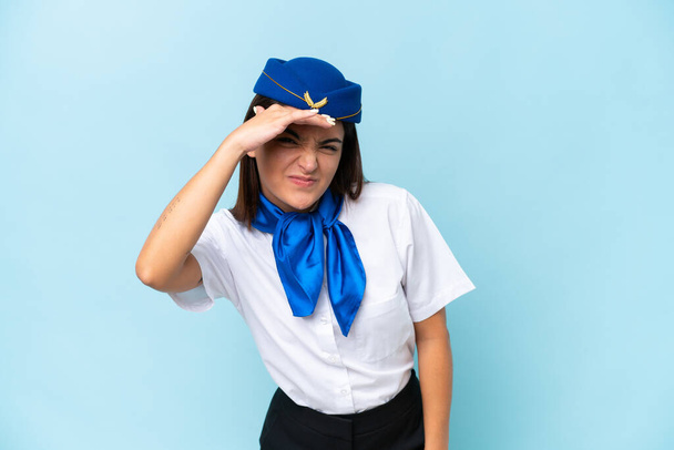 Airplane stewardess caucasian woman isolated on blue background looking far away with hand to look something - Photo, Image