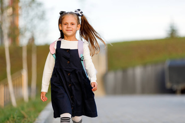 a little girl goes to school through the park along the path. distance education concept. school girl returning home from school - Φωτογραφία, εικόνα