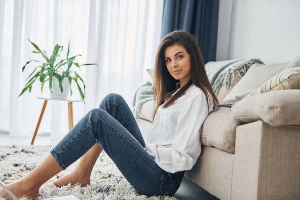 Beautiful young woman in jeans and white shirt is at home. - Fotografie, Obrázek