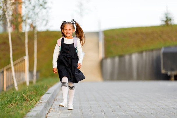 a little girl goes to school through the park along the path. distance education concept. school girl returning home from school - Φωτογραφία, εικόνα