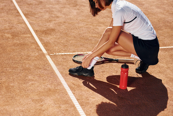 Wearing shoes. Female tennis player is on the court at daytime. - Foto, imagen