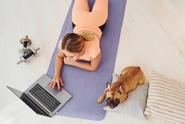Top view of woman with pug dog and laptop that is at home at daytime. - Fotoğraf, Görsel