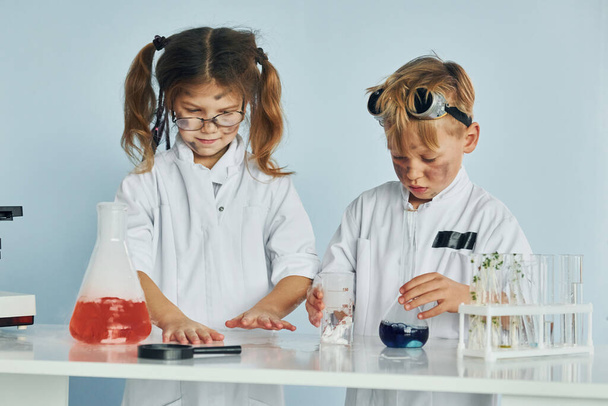 Little girl and boy in white coats plays a scientists in lab by using equipment. - Photo, Image