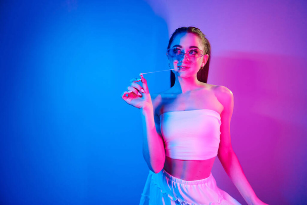 Positive emotions. Fashionable young woman standing in the studio with neon light. - Fotó, kép