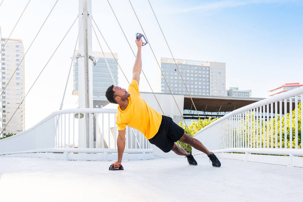 Black hispanic sportsman training outdoors in the city - African man with fit muscular body doing functional workout to train cardio, body muscles and abs core - Foto, Bild