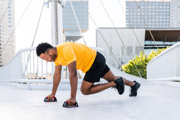 Black hispanic sportsman training outdoors in the city - African man with fit muscular body doing functional workout to train cardio, body muscles and abs core - Foto, immagini