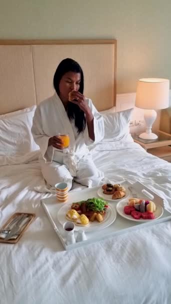 Ασιάτισσες τρώνε πρωινό στο κρεβάτι, γυναίκες στην κρεβατοκάμαρα τρώνε πρωινό το πρωί. με καφέ και φρούτα - Πλάνα, βίντεο