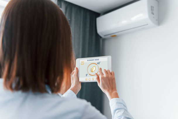 Modern technologies. Rear view of woman that is indoors controlling smart home. - Φωτογραφία, εικόνα
