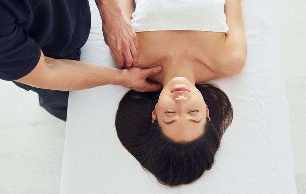 Молодая женщина лежит, когда мужчина делает массаж ее тела в спа. - Фото, изображение