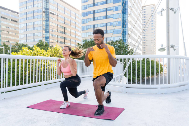Interracial sportive couple training outdoors - Multiracial couple wearing sportswear and doing functional workout outdoors to strenght body muscles, core abs, stamina and cardio - Foto, immagini