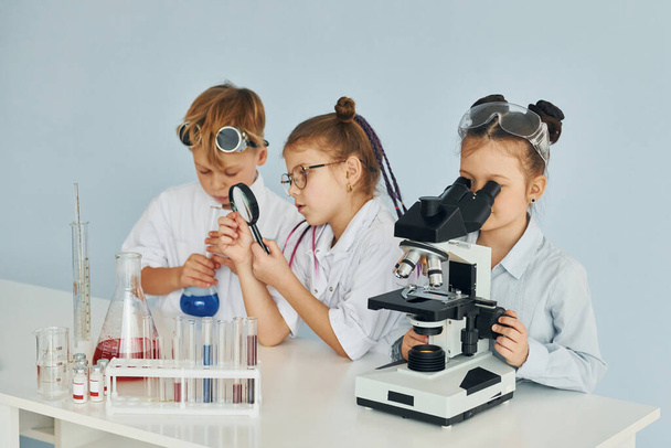 Children in white coats plays a scientists in lab by using equipment. - Fotó, kép