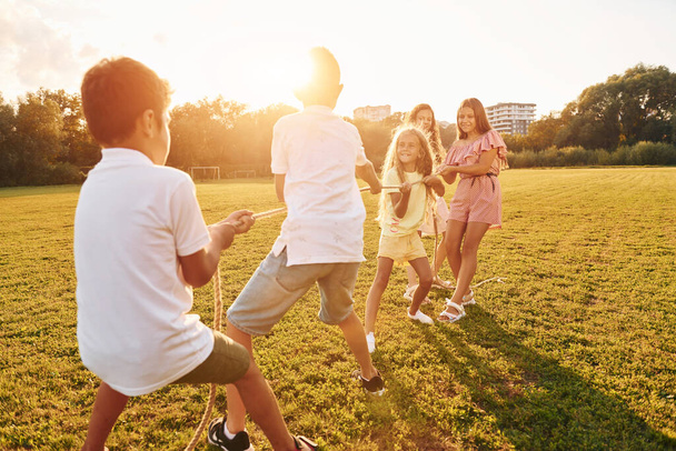 Having fun. Group of happy kids is outdoors on the sportive field at daytime. - Photo, image