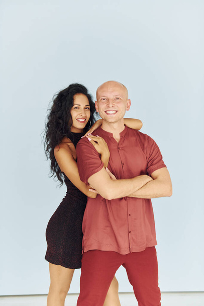 Standing in the studio against white background. Cheerful couple is together indoors. - Foto, imagen