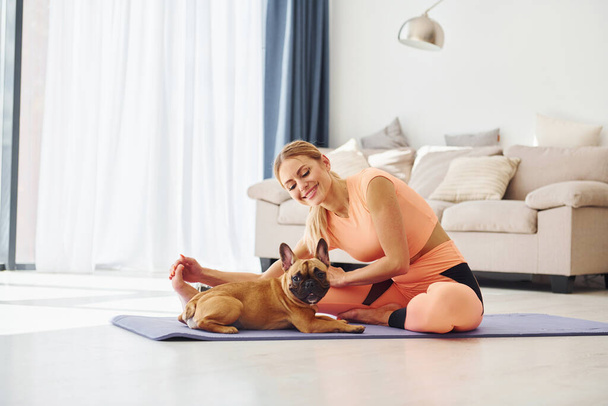 Yoga time. Woman with pug dog is at home at daytime. - Foto, Imagen