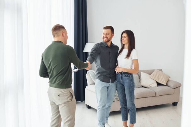 Salesman helps young couple in choosing an apartment. Conception of business and rent. - Photo, image