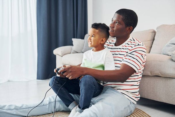 Playing video games. African american father with his young son at home. - Foto, Imagem