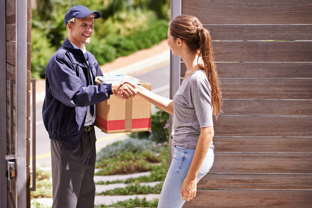 When she expects excellence she knows hell deliver the goods. a woman shaking hands with a friendly delivery man - Foto, afbeelding
