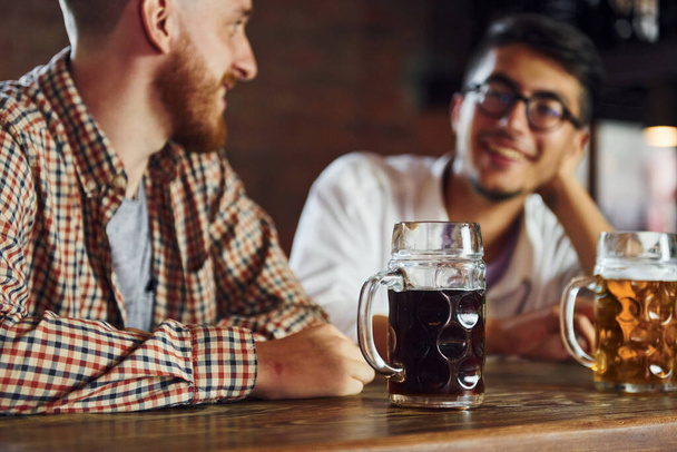 People in casual clothes sitting in the pub and having conversation. - 写真・画像