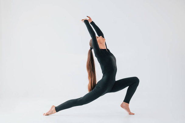 Professional exercises. Young woman in sportive clothes doing gymnastics indoors. - Fotó, kép