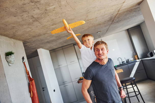 Yellow toy plane. Father and son is indoors at home together. - Fotoğraf, Görsel