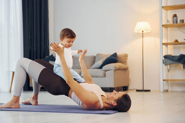 Doing fitness together. Mother with her little daughter is at home together. - Foto, imagen
