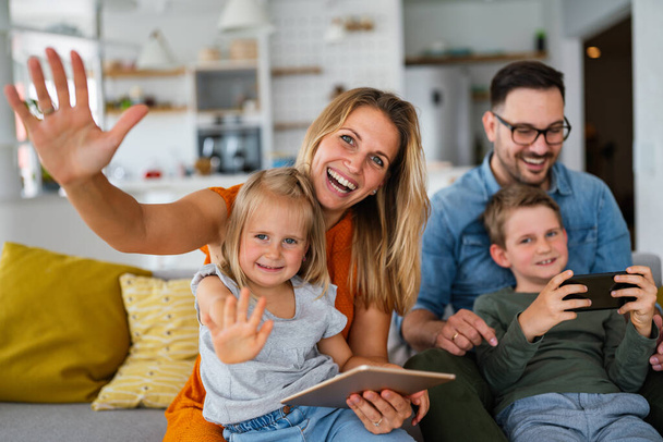 Happy young family having fun time at home. Parents with children using digital device. Education parenting happiness concept. - Фото, зображення