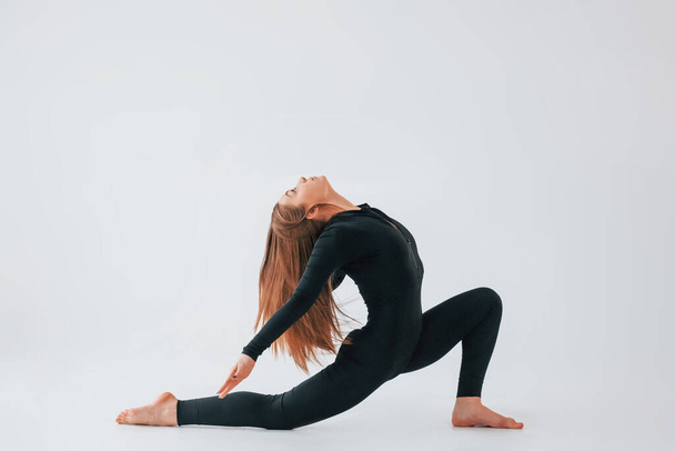 Side stretch. Young woman in sportive clothes doing gymnastics indoors. - Foto, Imagem