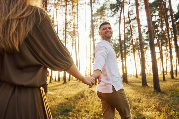 Having a walk. Happy couple is outdoors in the forest at daytime. - Fotoğraf, Görsel