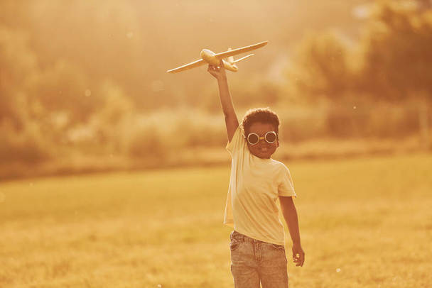 Power of imagination. Playing pilot game. African american kid have fun in the field at summer daytime. - Foto, imagen