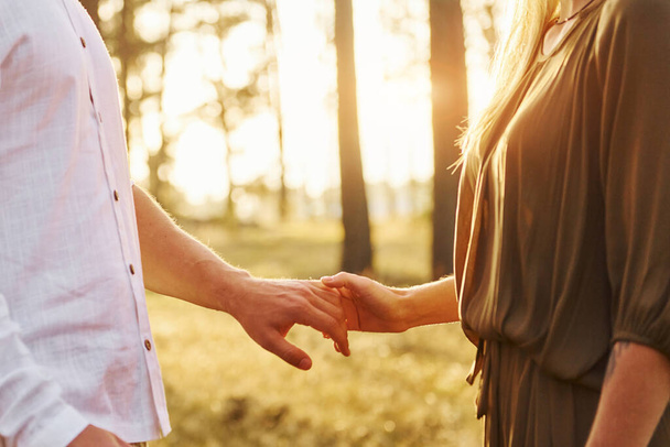 Focused view of hands. Happy couple is outdoors in the forest at daytime. - Foto, Imagen