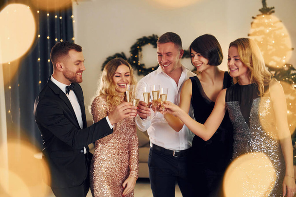Cheering with champagne. Group of people have a new year party indoors together. - Foto, imagen