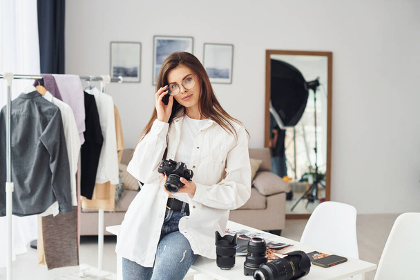 Female photographer in casual clothes is working indoors at daytime. - Foto, Imagen