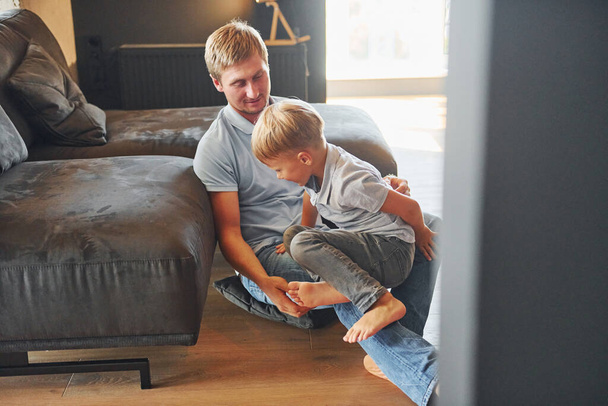 Having free time. Father and son is indoors at home together. - Foto, imagen
