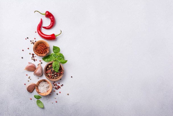 Top view of peppercorn, salt, garlic, basil and red hot chilli pepper for spicy and aromatic food on grey concrete background with copy space - Foto, afbeelding