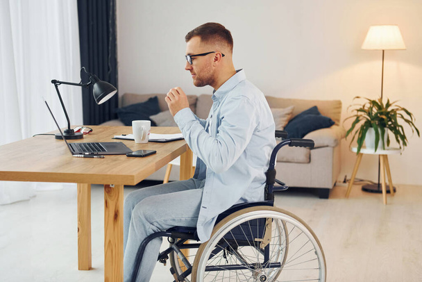 Práce pomocí notebooku. Zdravotně postižený muž na vozíku je doma. - Fotografie, Obrázek