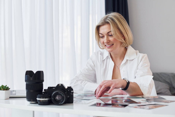 Middle-aged woman in elegant clothes is at home. Photographer with camera. - Photo, image
